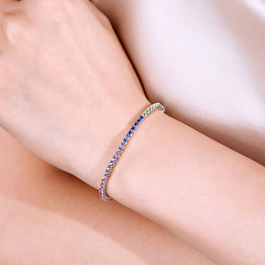 S925 sterling silver tennis bracelet featuring a continuous gradient line of 2.0mm round cut colorful rainbow sapphires with a secure box clasp.