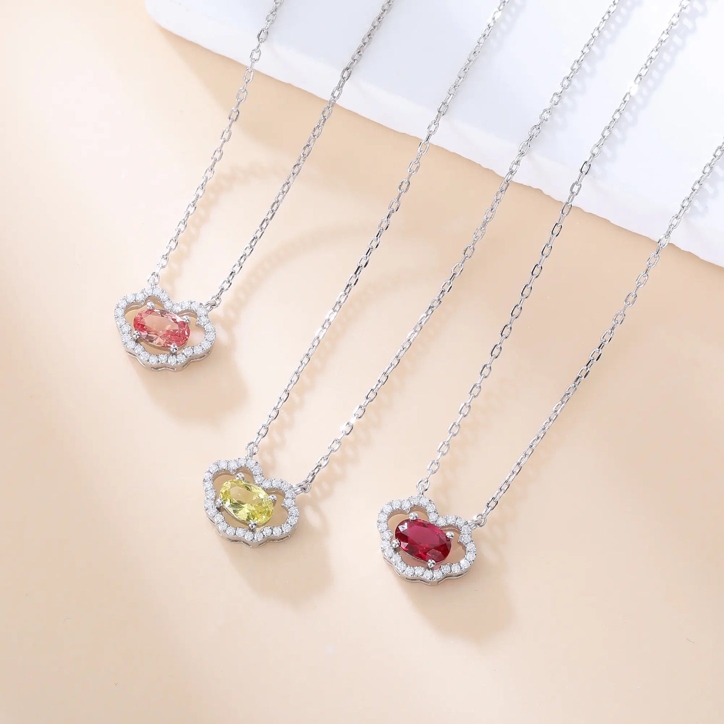 A sterling silver chain necklace featuring a traditional Chinese auspicious Ruyi cloud pendant, encrusted with pavé accents and centered with an oval-cut padparadscha sapphire.