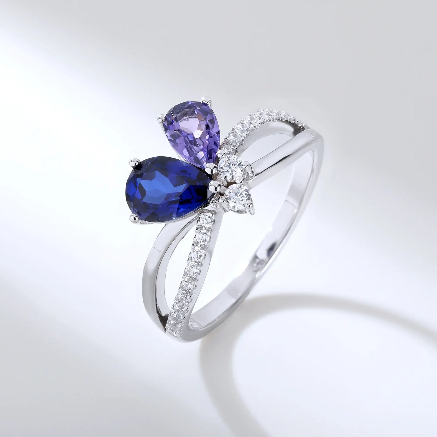 S925 sterling silver criss-cross ring with pear-cut royal blue and lavender sapphires forming a butterfly with a sparkling accent at the center.