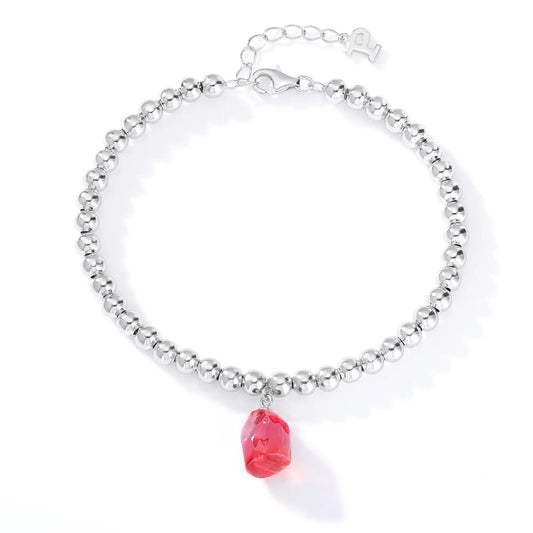 A row of polished sterling silver beads strung into a wrist bracelet, adorned with a translucent bright pink freeform sapphire drop.
