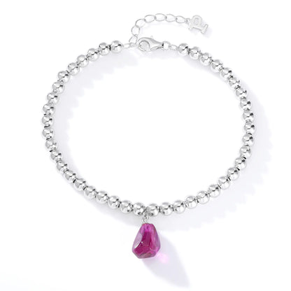 Silver beaded bracelet with a glossy finish featuring a suspended freeform magenta-purple gemstone pendant charm.