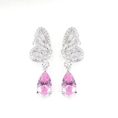 Elegant sterling silver dangle earrings featuring detailed pavé butterfly wings holding vibrant pear-cut pink sapphire stones that catch the light beautifully.