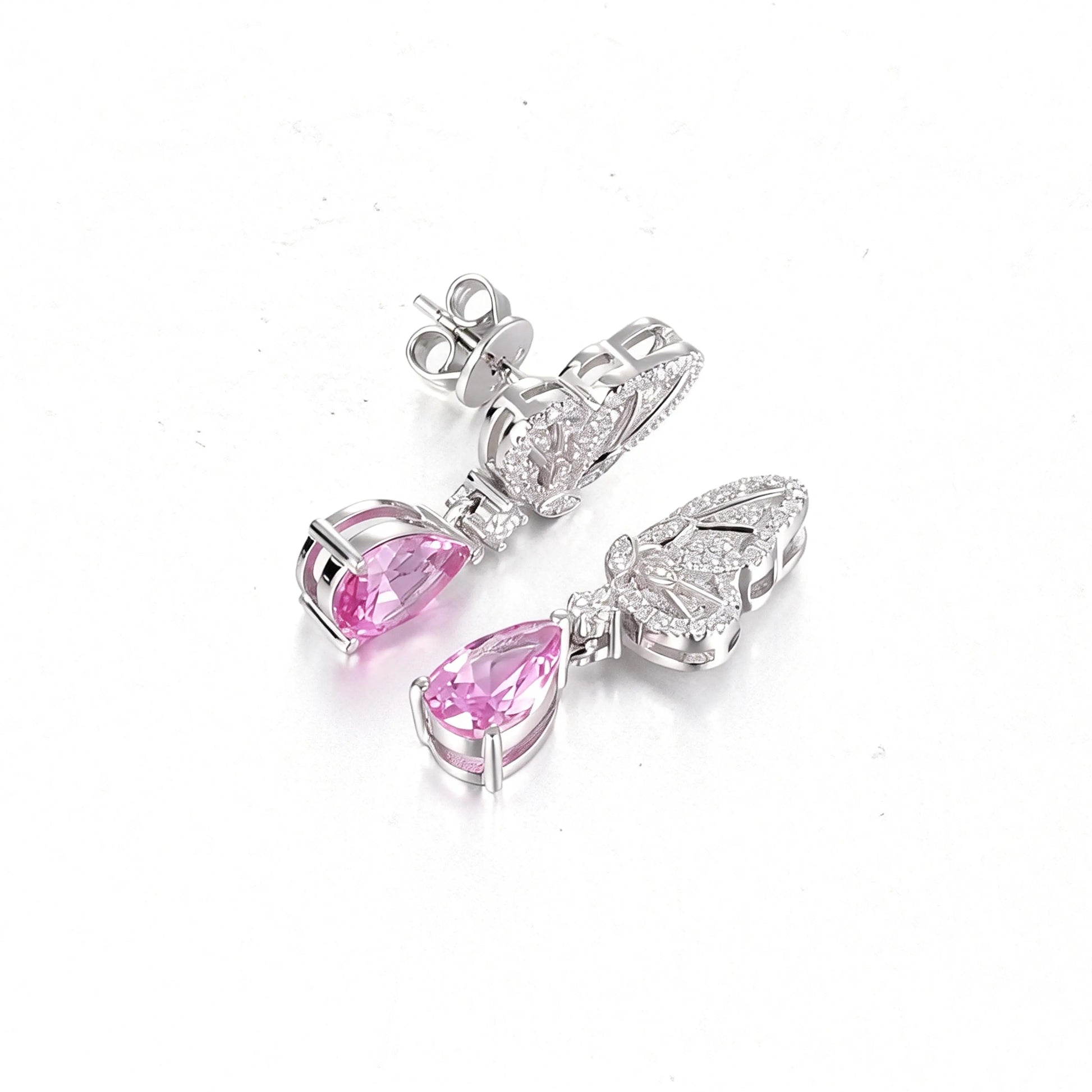 Elegant sterling silver dangle earrings featuring detailed pavé butterfly wings holding vibrant pear-cut pink sapphire stones that catch the light beautifully.