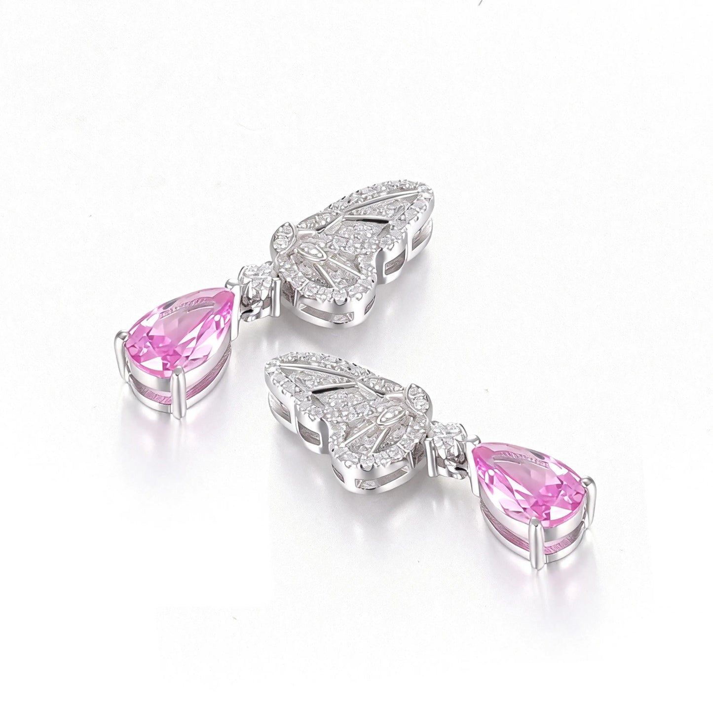 Elegant sterling silver dangle earrings featuring detailed pavé butterfly wings holding vibrant pear-cut pink sapphire stones that catch the light beautifully.
