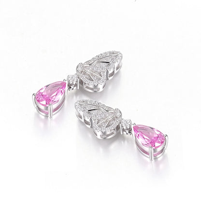 Elegant sterling silver dangle earrings featuring detailed pavé butterfly wings holding vibrant pear-cut pink sapphire stones that catch the light beautifully.