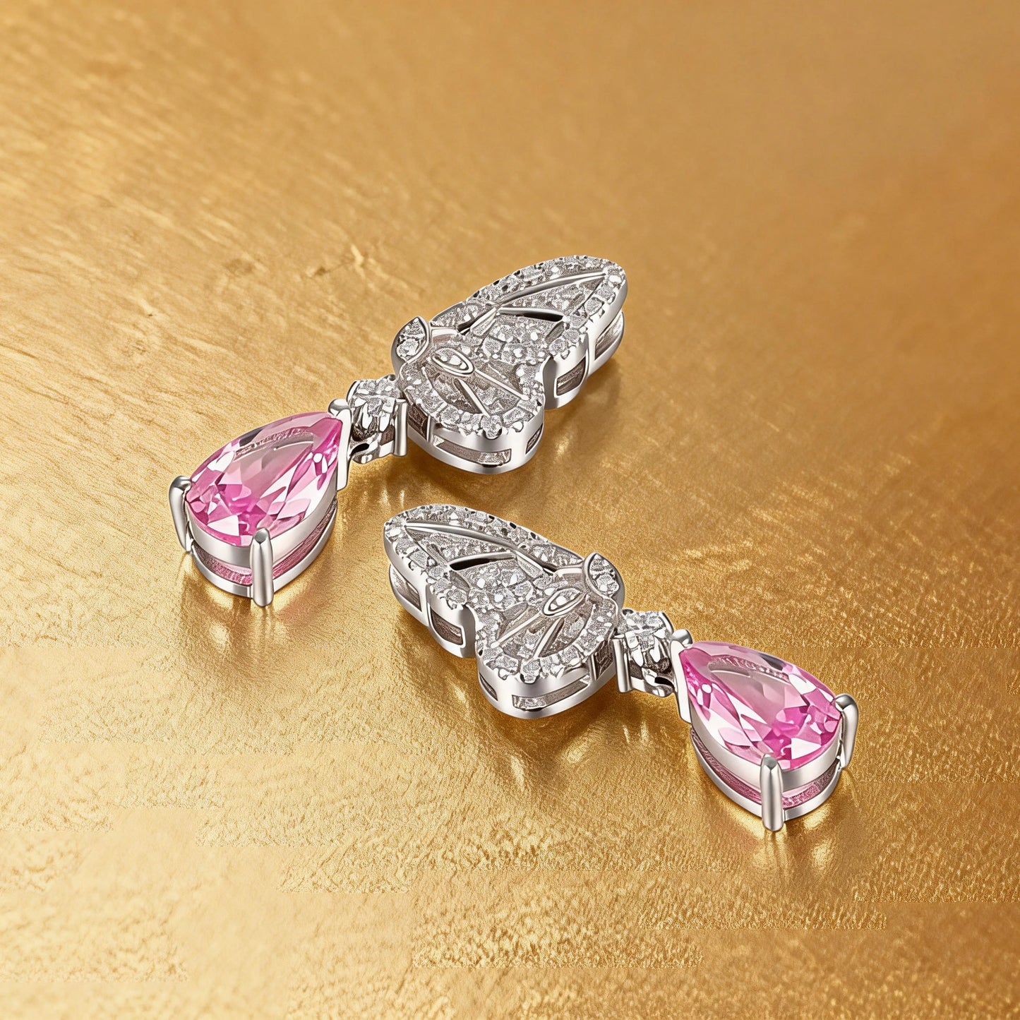 Elegant sterling silver dangle earrings featuring detailed pavé butterfly wings holding vibrant pear-cut pink sapphire stones that catch the light beautifully.