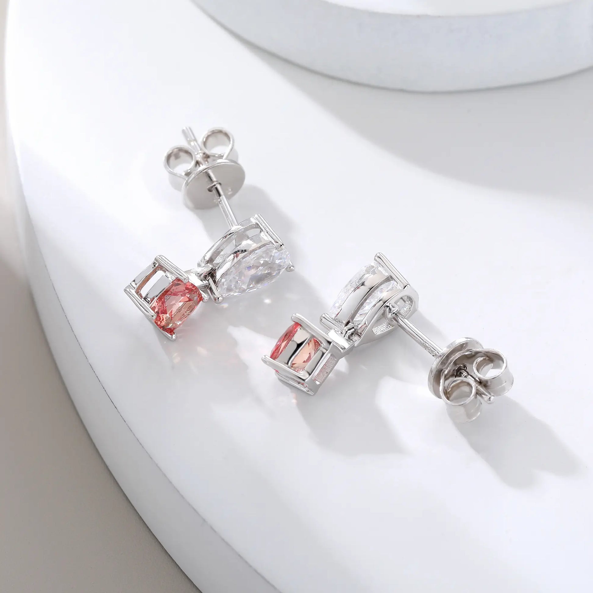 S925 sterling silver drop earrings featuring a sparkling white pear-cut moissanite at the post, dangling a square cushion-cut pink sapphire suspended by a minimalist geometric silver loop.