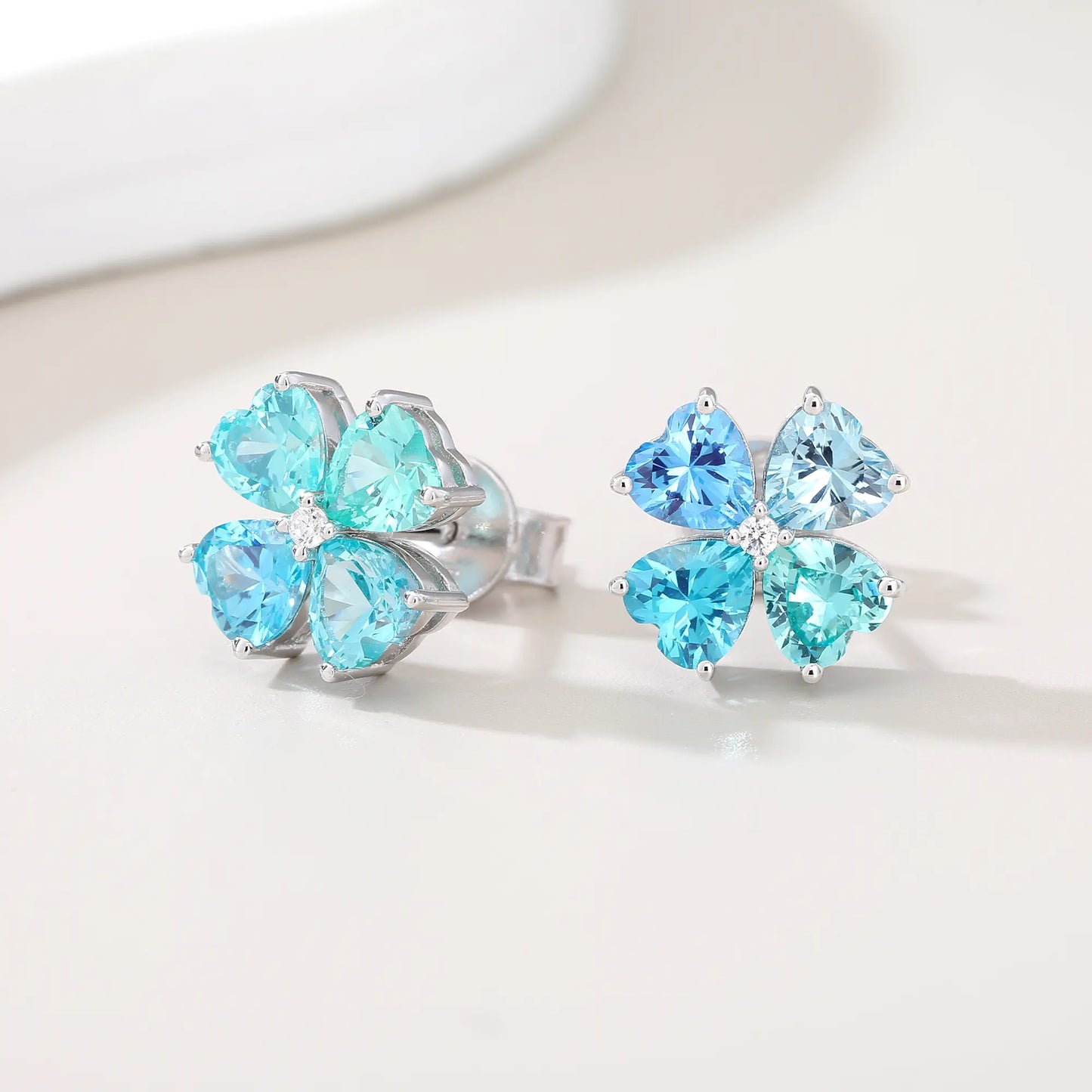 S925 sterling silver stud earrings featuring four heart-cut ocean blue moissanite gemstones forming a lucky four-leaf clover with a sparkling center moissanite.