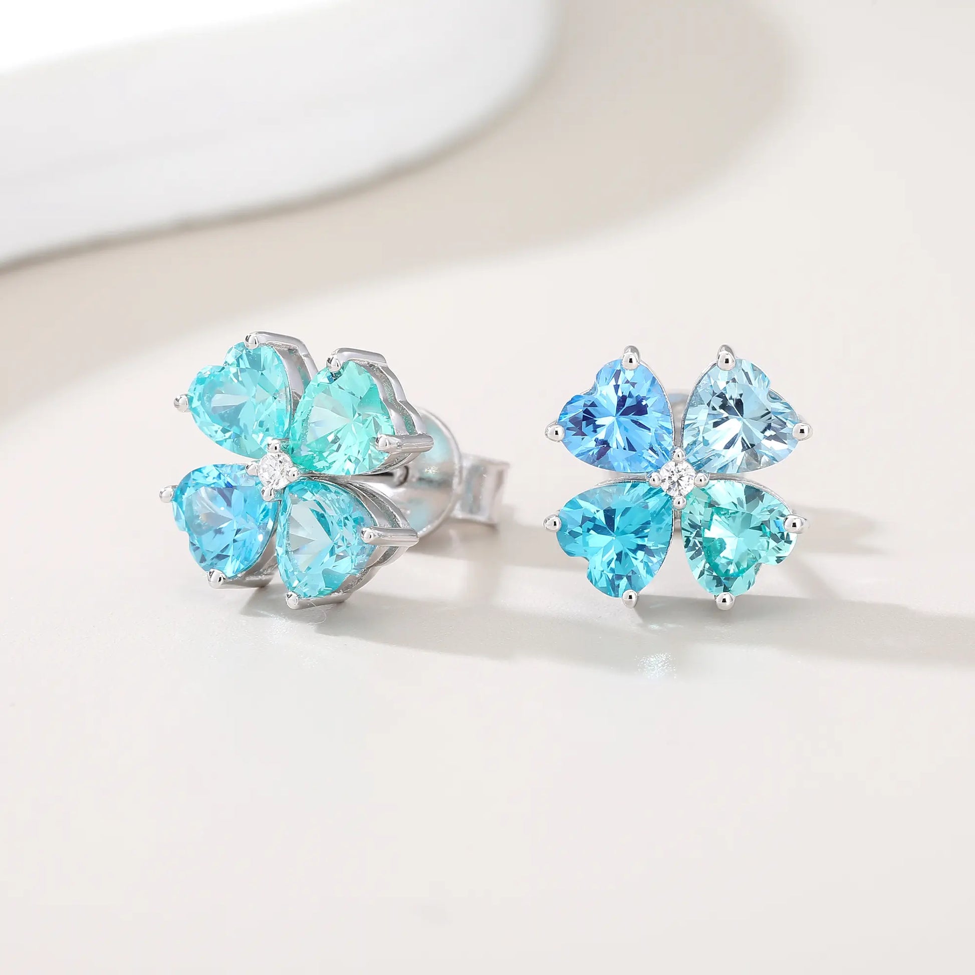 S925 sterling silver stud earrings featuring four heart-cut ocean blue moissanite gemstones forming a lucky four-leaf clover with a sparkling center moissanite.