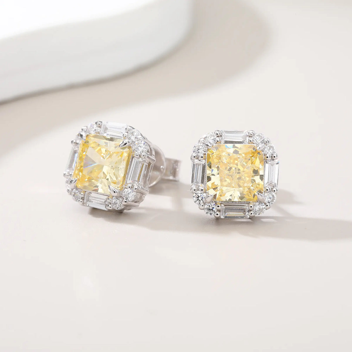 Cushion crushed ice cut canary yellow moissanite stud earrings featuring baguette and round moissanite halo setting.