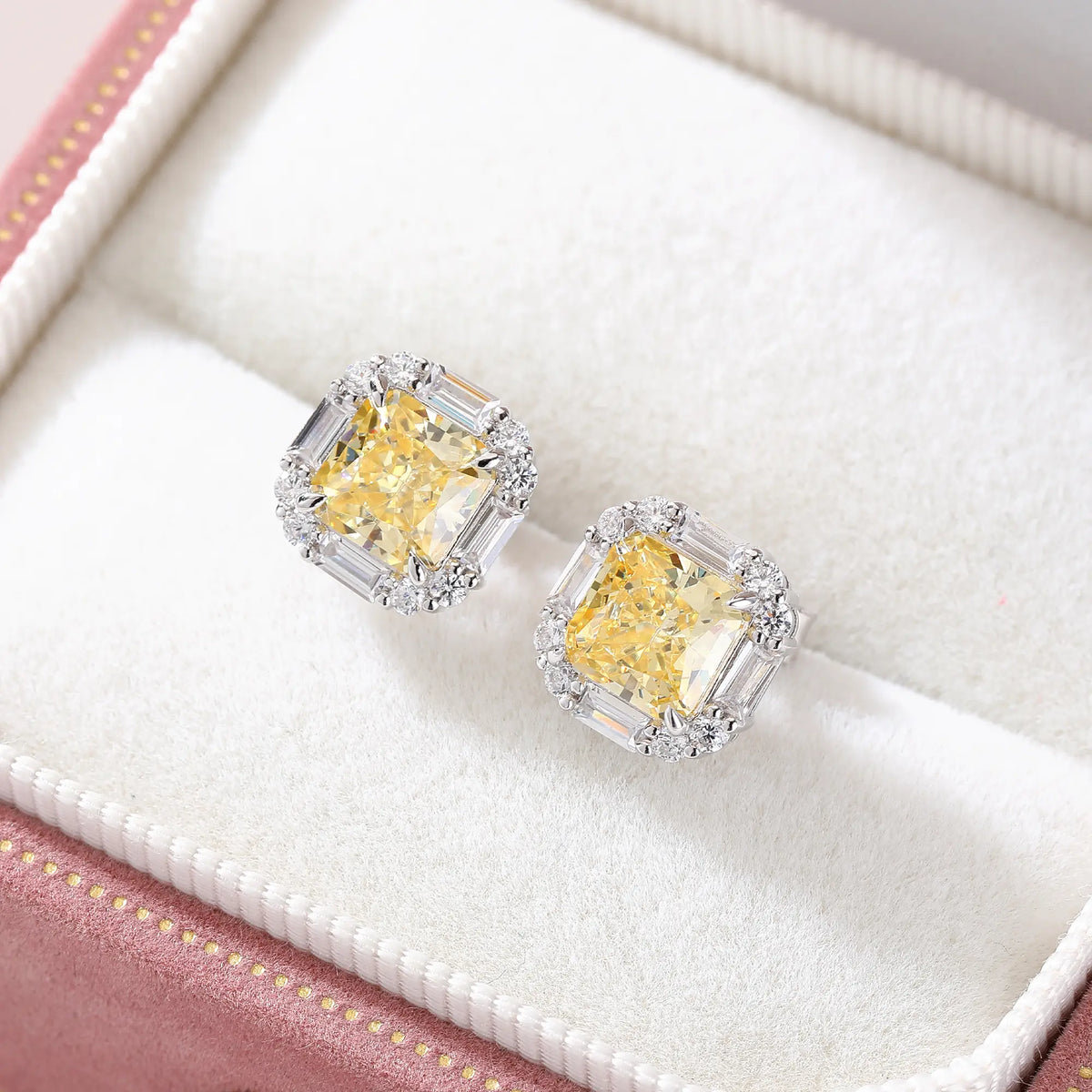 Cushion crushed ice cut canary yellow moissanite stud earrings featuring baguette and round moissanite halo setting.