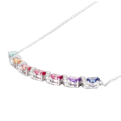 A curved rainbow pendant necklace featuring seven oval cut multi-color sapphires separated by diamond-encrusted silver swirl links, set against a crisp white background.