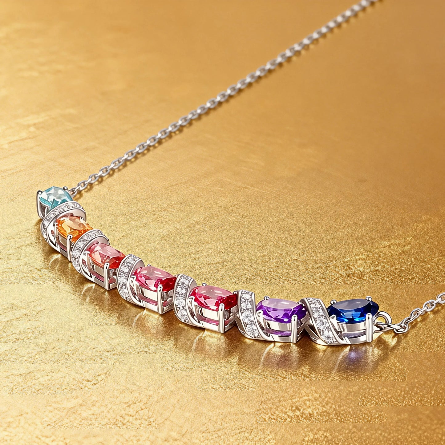 A curved rainbow pendant necklace featuring seven oval cut multi-color sapphires separated by diamond-encrusted silver swirl links, set against a crisp white background.