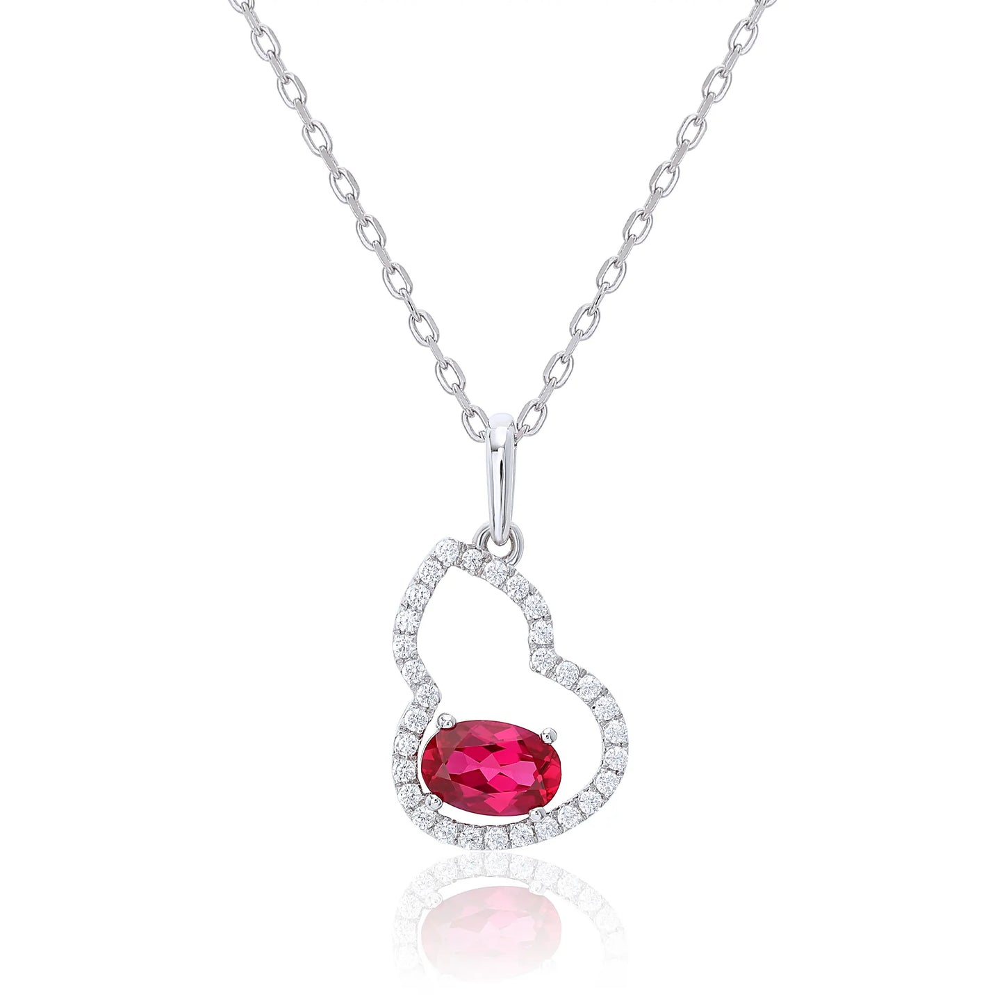 An openwork gourd pendant necklace paved with sparkling cz stones, featuring a horizontally set oval cut ruby at the base, resting on a white reflective surface.