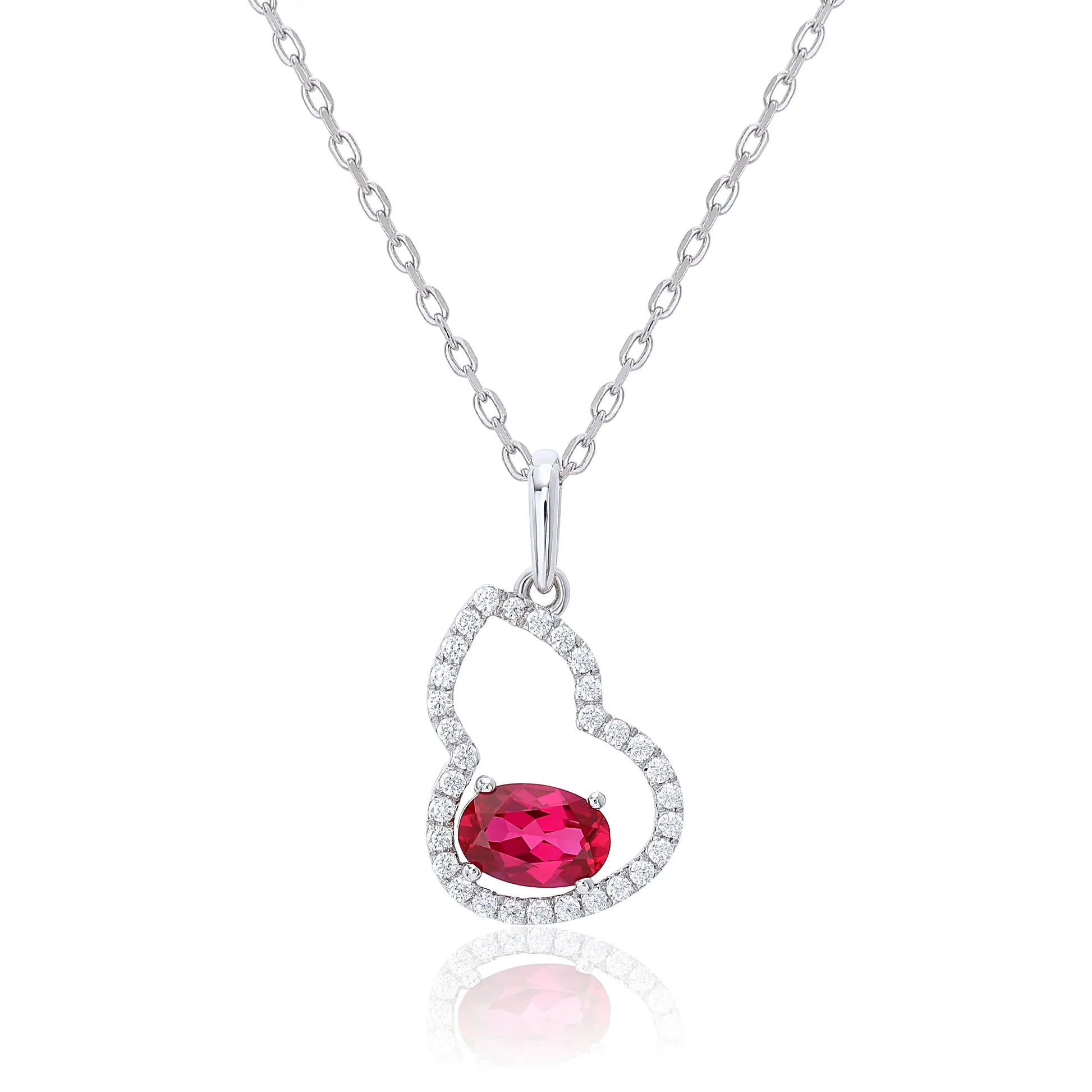 An openwork gourd pendant necklace paved with sparkling cz stones, featuring a horizontally set oval cut ruby at the base, resting on a white reflective surface.