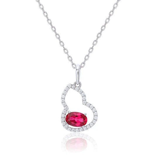 An openwork gourd pendant necklace paved with sparkling cz stones, featuring a horizontally set oval cut ruby at the base, resting on a white reflective surface.