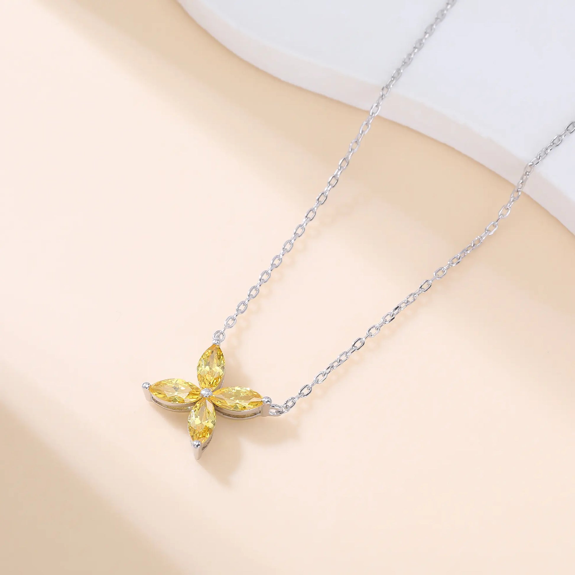 A sterling silver chain necklace featuring a classic minimalist four-leaf clover flower pendant crafted with four brilliant marquise-cut yellow moissanite gemstones.