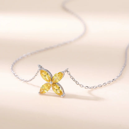 A sterling silver chain necklace featuring a classic minimalist four-leaf clover flower pendant crafted with four brilliant marquise-cut yellow moissanite gemstones.