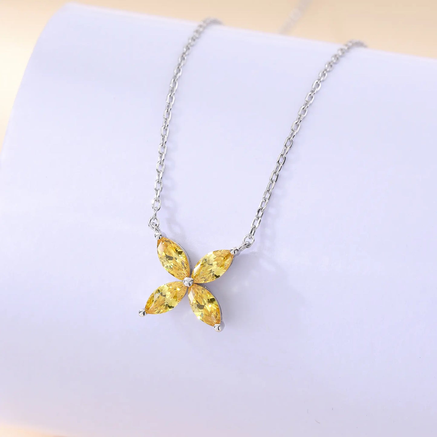 A sterling silver chain necklace featuring a classic minimalist four-leaf clover flower pendant crafted with four brilliant marquise-cut yellow moissanite gemstones.