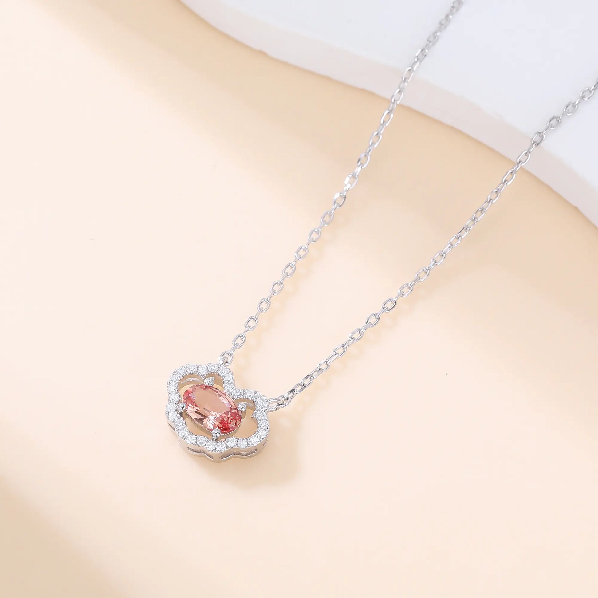 A sterling silver chain necklace featuring a traditional Chinese auspicious Ruyi cloud pendant, encrusted with pavé accents and centered with an oval-cut padparadscha sapphire.