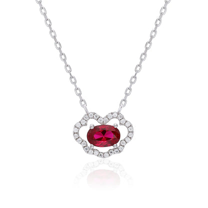 A sterling silver chain necklace featuring a traditional Chinese auspicious Ruyi cloud pendant, encrusted with pavé accents and centered with a vibrant oval-cut red ruby gemstone.