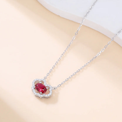 A sterling silver chain necklace featuring a traditional Chinese auspicious Ruyi cloud pendant, encrusted with pavé accents and centered with a vibrant oval-cut red ruby gemstone.