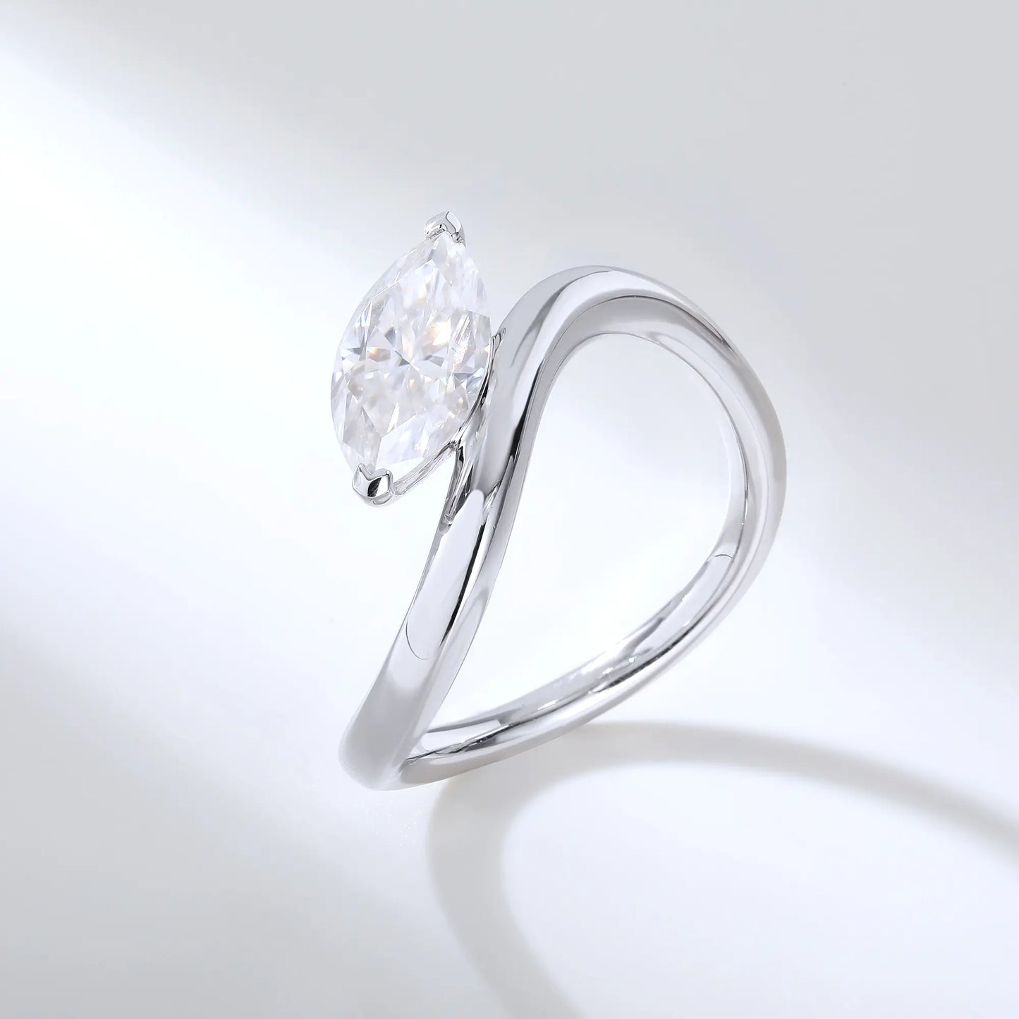 A sterling silver solitaire ring featuring a brilliant marquise-cut white moissanite stone, nestled within a modern fluid bypass twisted wave band.