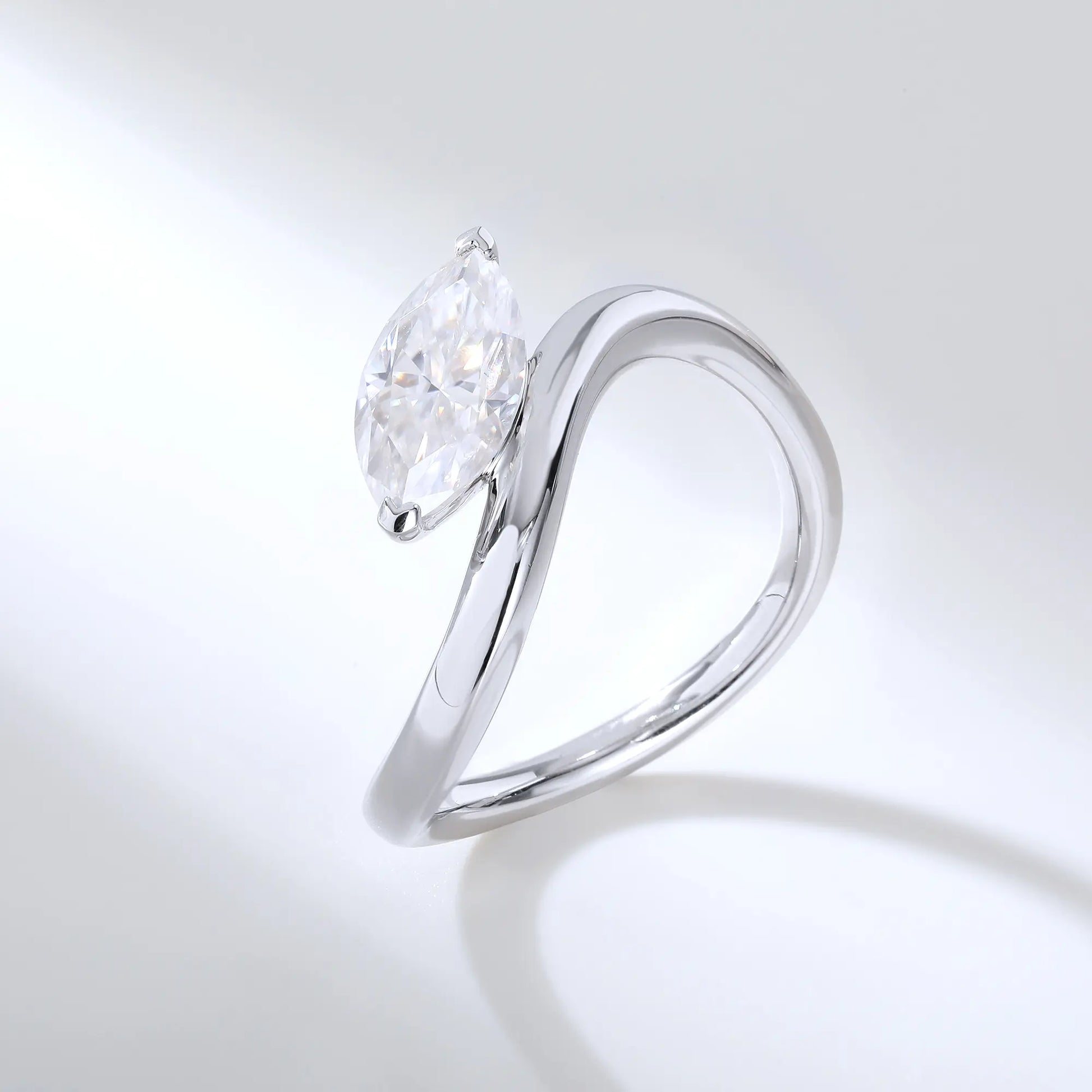 A sterling silver solitaire ring featuring a brilliant marquise-cut white moissanite stone, nestled within a modern fluid bypass twisted wave band.