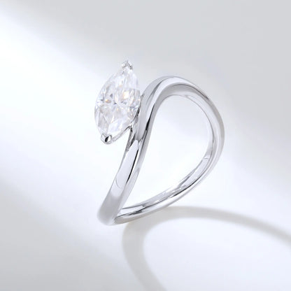 A sterling silver solitaire ring featuring a brilliant marquise-cut white moissanite stone, nestled within a modern fluid bypass twisted wave band.