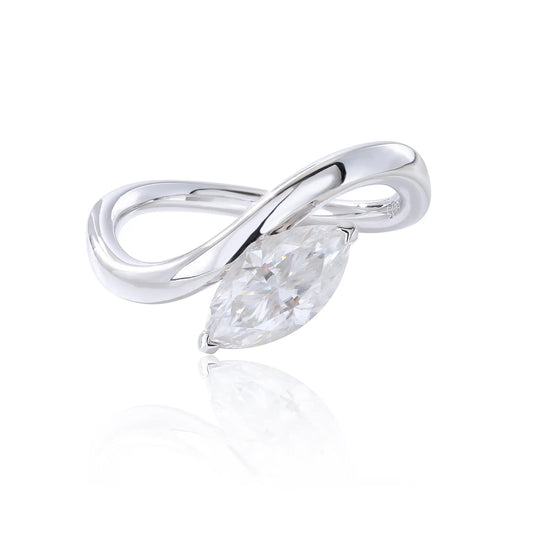 A sterling silver solitaire ring featuring a brilliant marquise-cut white moissanite stone, nestled within a modern fluid bypass twisted wave band.