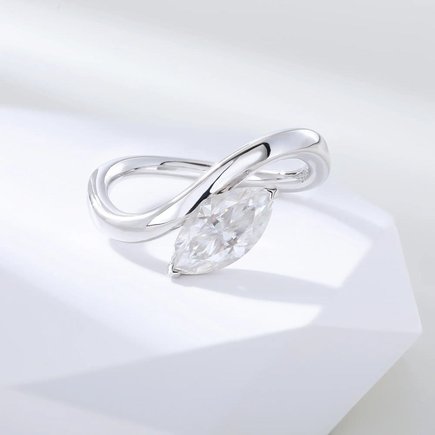 A sterling silver solitaire ring featuring a brilliant marquise-cut white moissanite stone, nestled within a modern fluid bypass twisted wave band.