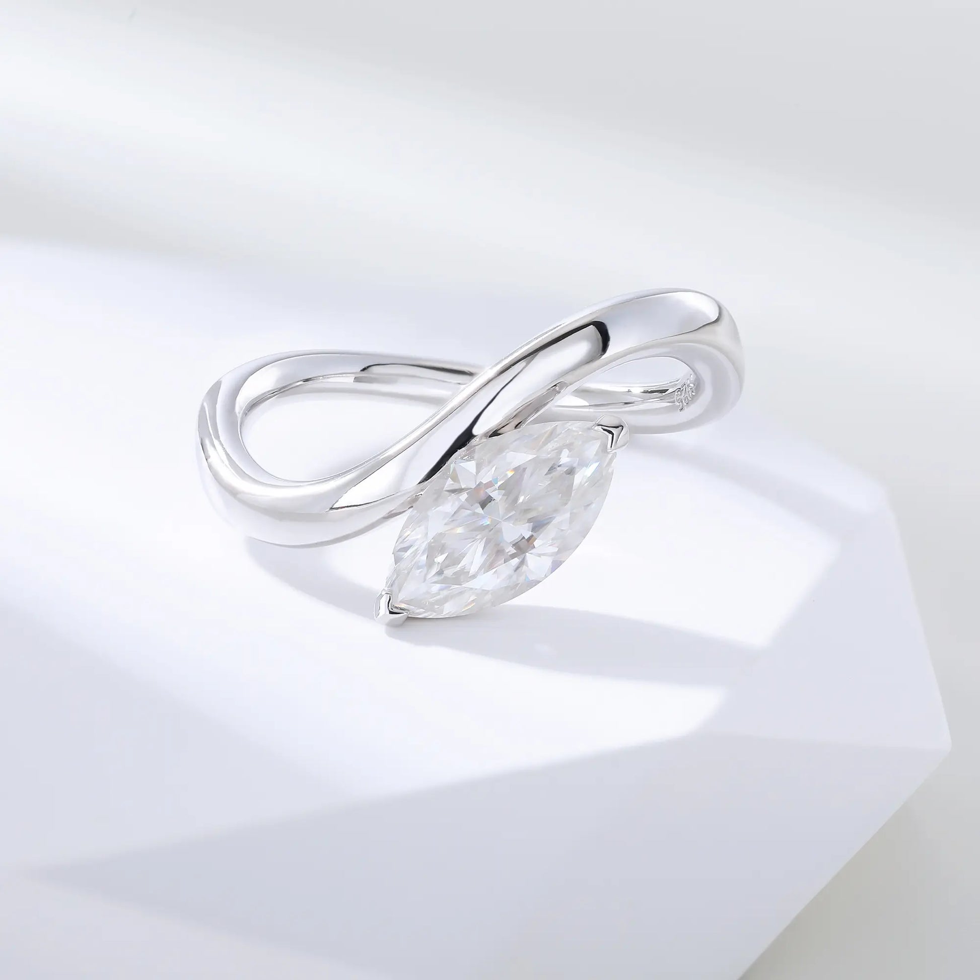 A sterling silver solitaire ring featuring a brilliant marquise-cut white moissanite stone, nestled within a modern fluid bypass twisted wave band.