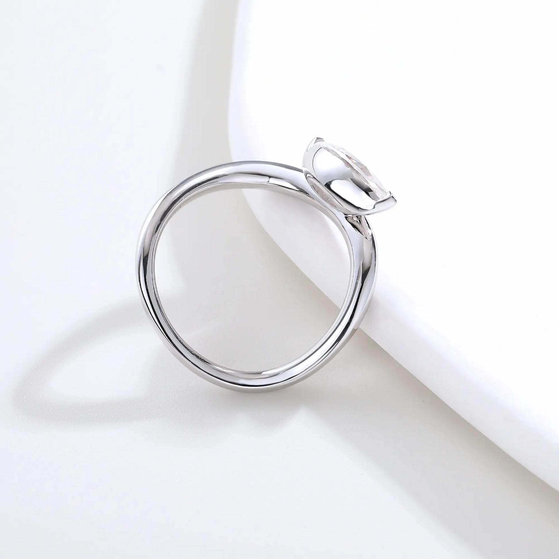 A sterling silver solitaire ring featuring a brilliant marquise-cut white moissanite stone, nestled within a modern fluid bypass twisted wave band.