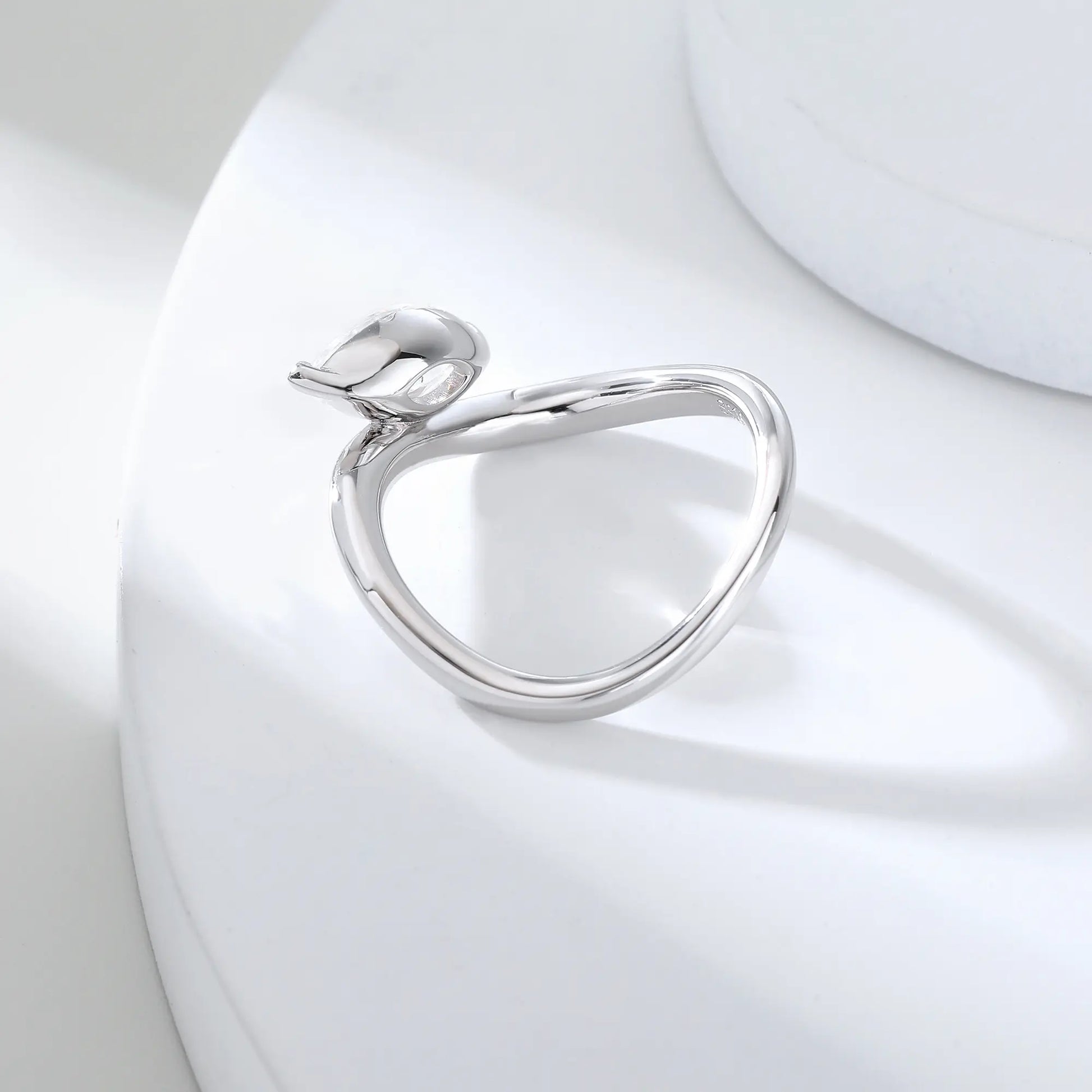 A sterling silver solitaire ring featuring a brilliant marquise-cut white moissanite stone, nestled within a modern fluid bypass twisted wave band.