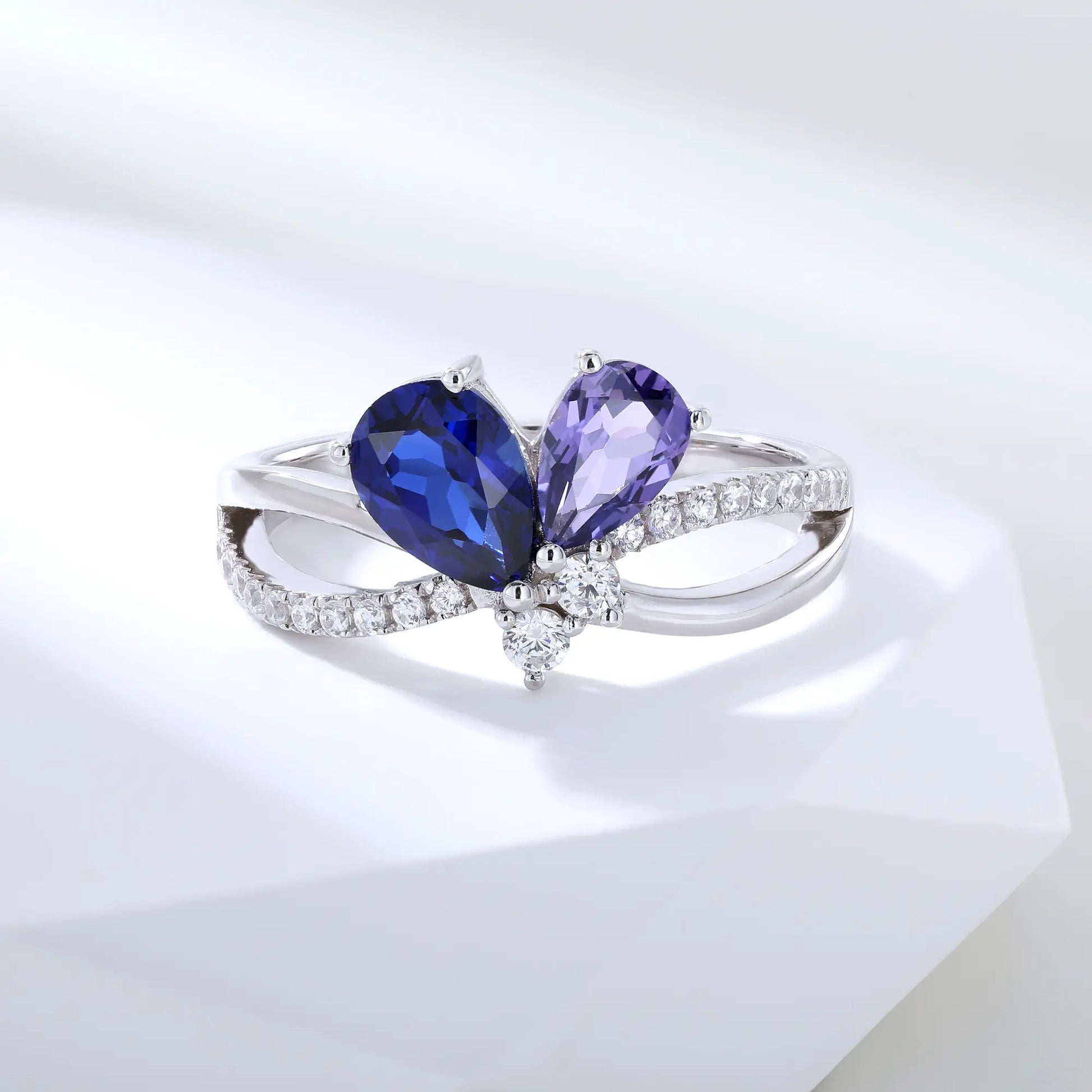 S925 sterling silver criss-cross ring with pear-cut royal blue and lavender sapphires forming a butterfly with a sparkling accent at the center.