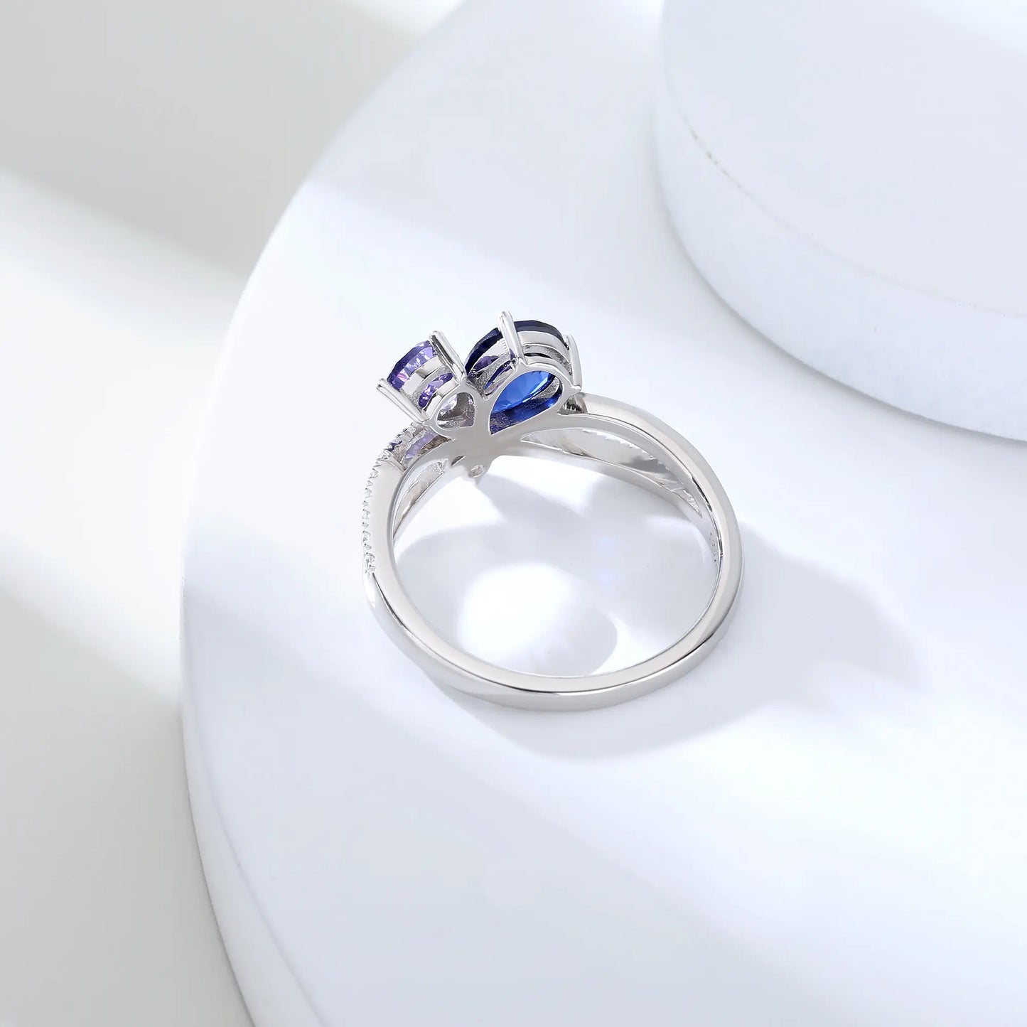 S925 sterling silver criss-cross ring with pear-cut royal blue and lavender sapphires forming a butterfly with a sparkling accent at the center.