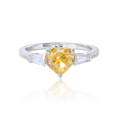 S925 sterling silver three-stone ring featuring a heart-cut yellow sapphire center stone flanked by tapered baguette cut moissanites on a pavé band.