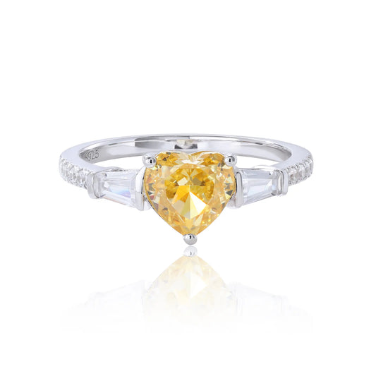 S925 sterling silver three-stone ring featuring a heart-cut yellow sapphire center stone flanked by tapered baguette cut moissanites on a pavé band.