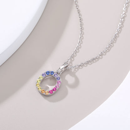 A delicate sterling silver cable chain necklace displaying a circular capital letter O pendant beautifully encrusted with a continuous rainbow gradient of multi-color lab sapphires.