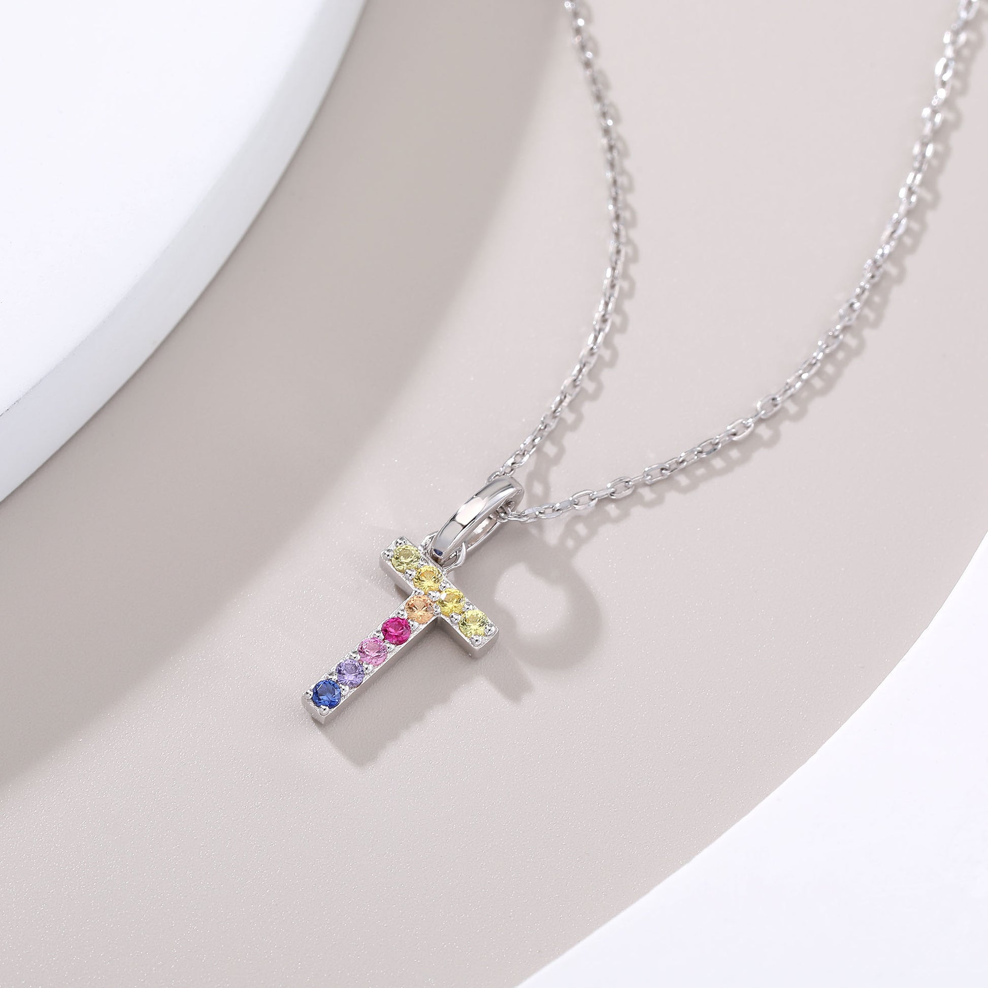 A minimal sterling silver cable chain necklace presenting an uppercase letter T pendant intricately hand-set with a horizontal and vertical rainbow gradient of round lab sapphires.