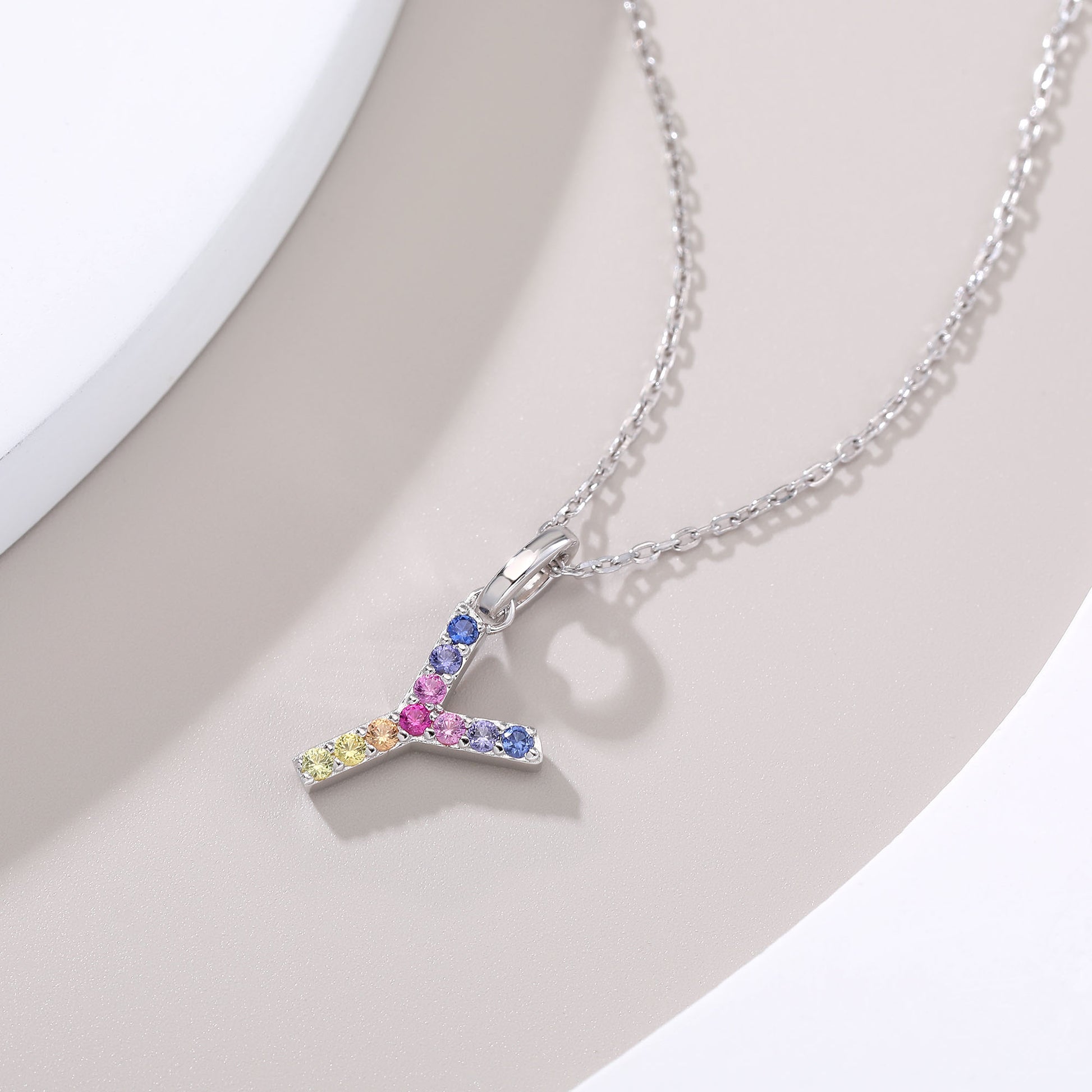 A solid sterling silver cable chain necklace showcasing an uppercase letter Y pendant intricately hand-set with a branching rainbow gradient of round multi-color lab sapphires.
