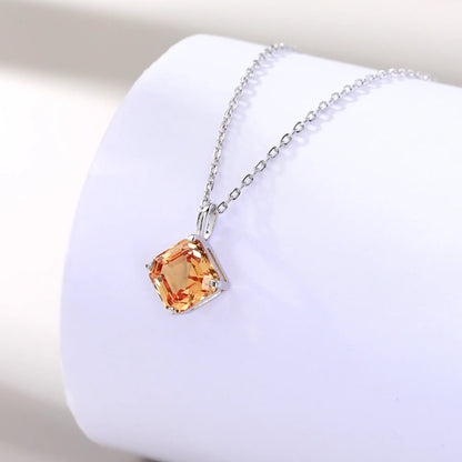 An elegant Asscher cut sapphire pendant necklace in champagne yellow, secured in a four-prong sterling silver setting with a delicate chain and reflective shadow below.