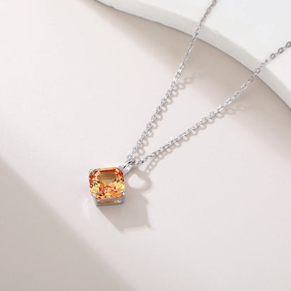 An elegant Asscher cut sapphire pendant necklace in champagne yellow, secured in a four-prong sterling silver setting with a delicate chain and reflective shadow below.